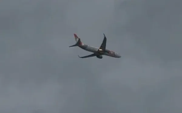 Avião da Gol visto de baixo, com ponto de fogo no motor, durante voo sobre o Grande Recife