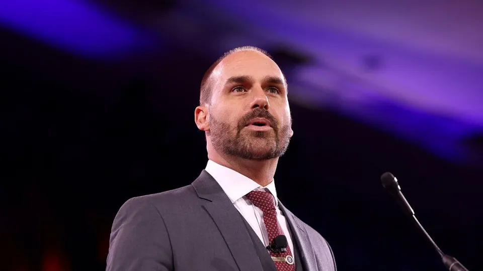 Eduardo Bolsonaro, de terno cinza e gravata vermelha, discursa em um púlpito