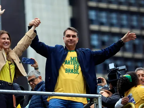 Flávio Bolsonaro acena para apoiadores em cima de um carro de som
