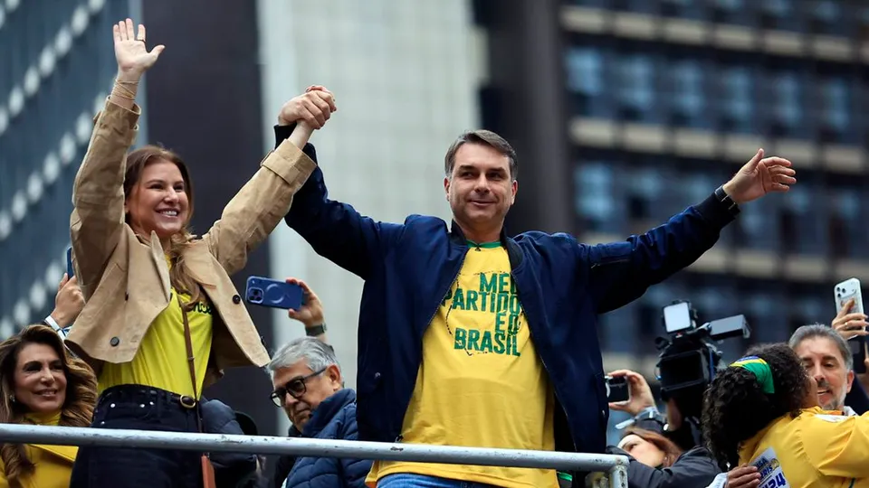 Flávio Bolsonaro acena para apoiadores em cima de um carro de som